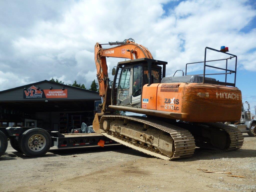 a large orange excavator being towed by a trailer